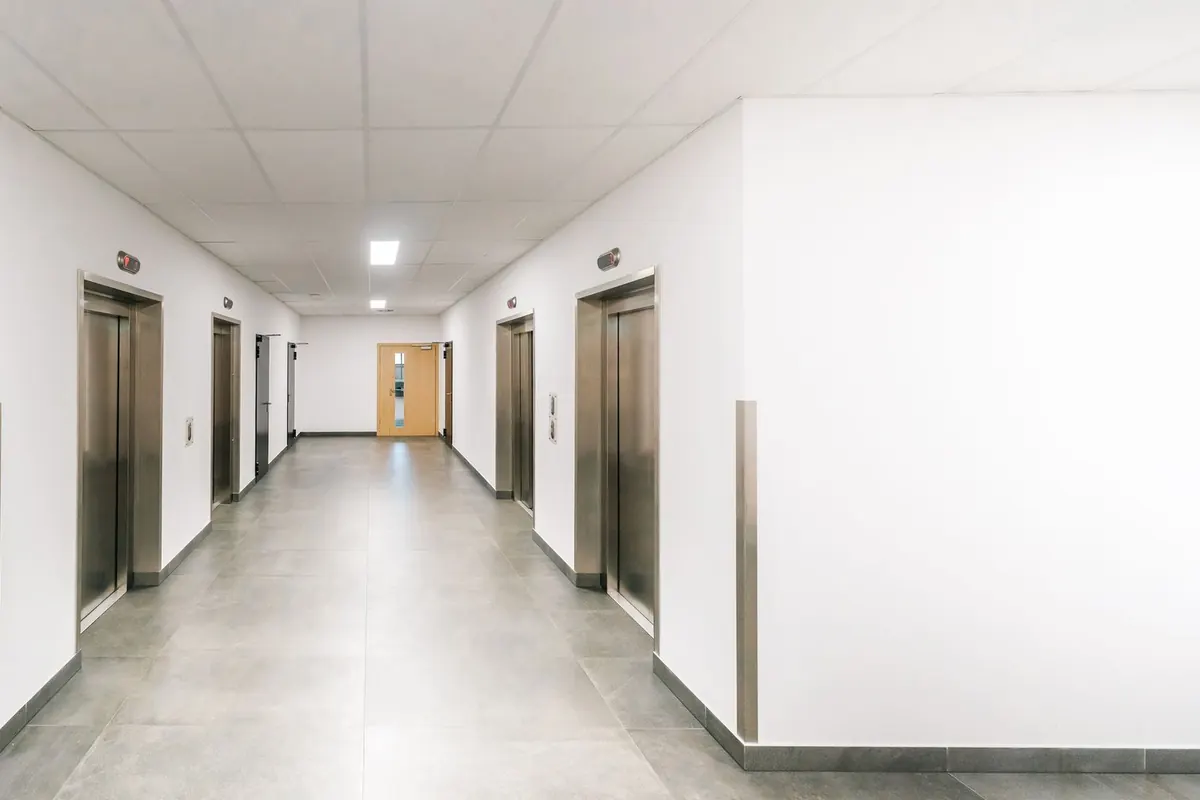 Bright corridor with elevator doors on both sides.